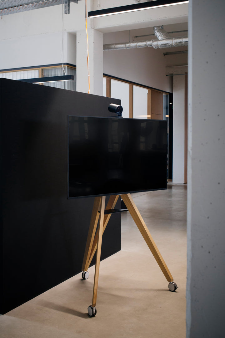 TV Ständer auf Rollen aus Holz vor im Büro